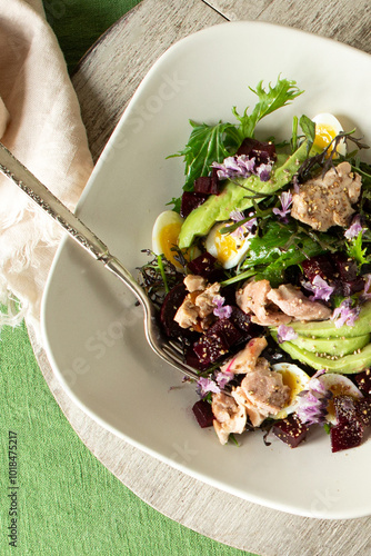 plate with salad with cod liver, avocado and beetroot on a light table