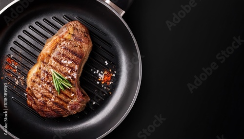 Grilled steak on a frying pan with herbs against a dark background. photo