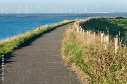 path on the dike, wind turbines in the background
