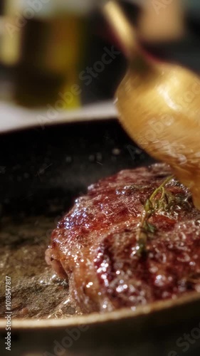 Close-up of a juicy steak roasting in a hot pan inside a restaurant kitchen