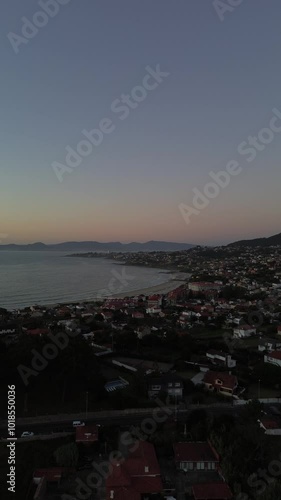 Aerial view of Patos and Prado beaches with houses above, after sunset. Toralla island and Vigo estuary are visible in the distance. Monteferro obscures the view as camera descends to Area Fofa beach. photo