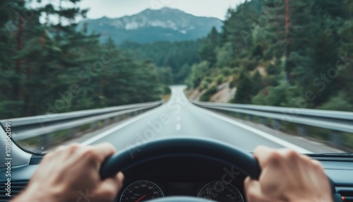 Hands gripping steering wheel while driving on a winding road through mountainous terrain photo