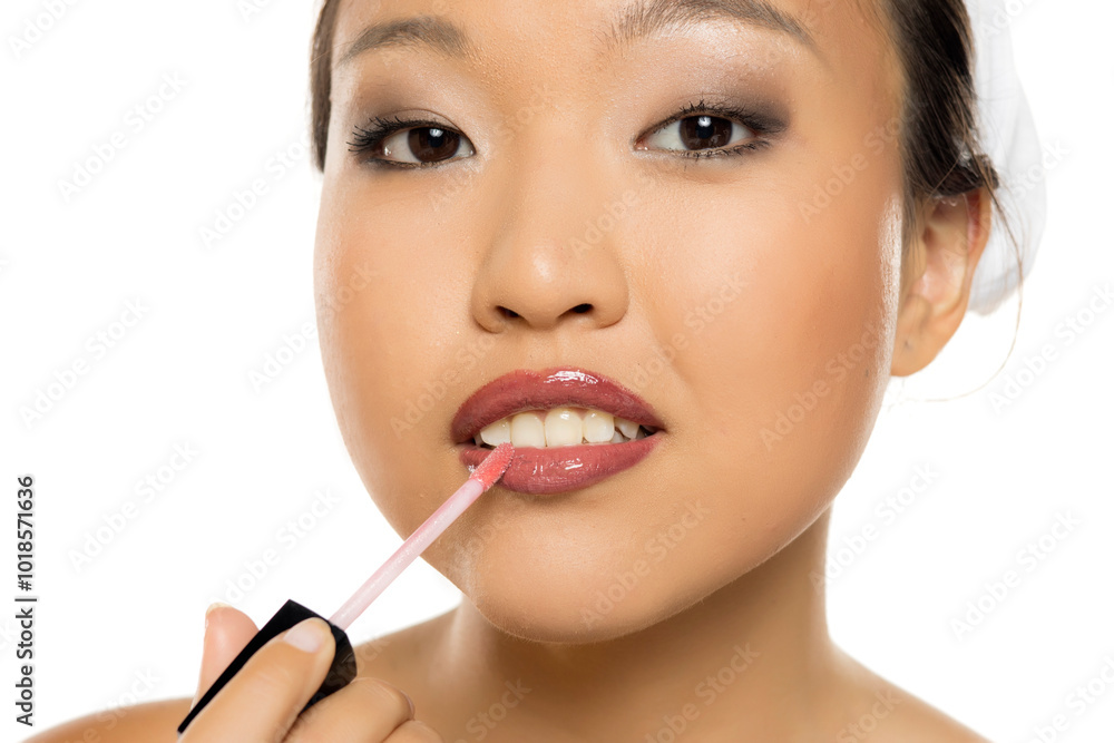 Closeup portrait of a young Asian woman applying lipgloss. Closeup portrait of a young Asian woman applying lipgloss.