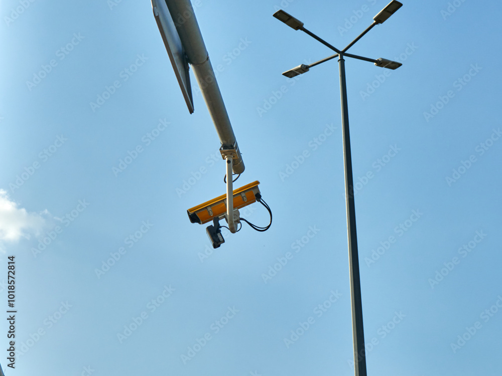 CCTV camera on a street light pole with blue sky background. CCTV camera on a street light pole with blue sky background.