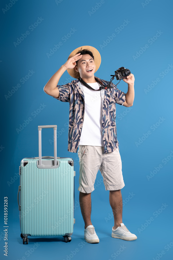 Full body image of Asian guy using camera to travel and posing on blue background Full body image of Asian guy using camera to travel and posing on blue background
