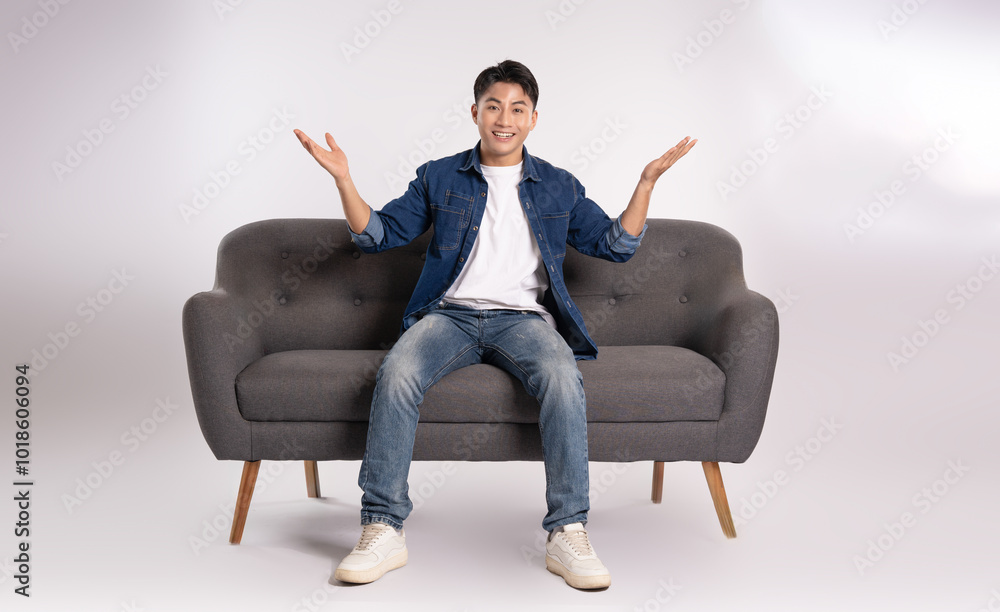 Full body image of young Asian man posing on sofa on white background Full body image of young Asian man posing on sofa on white background