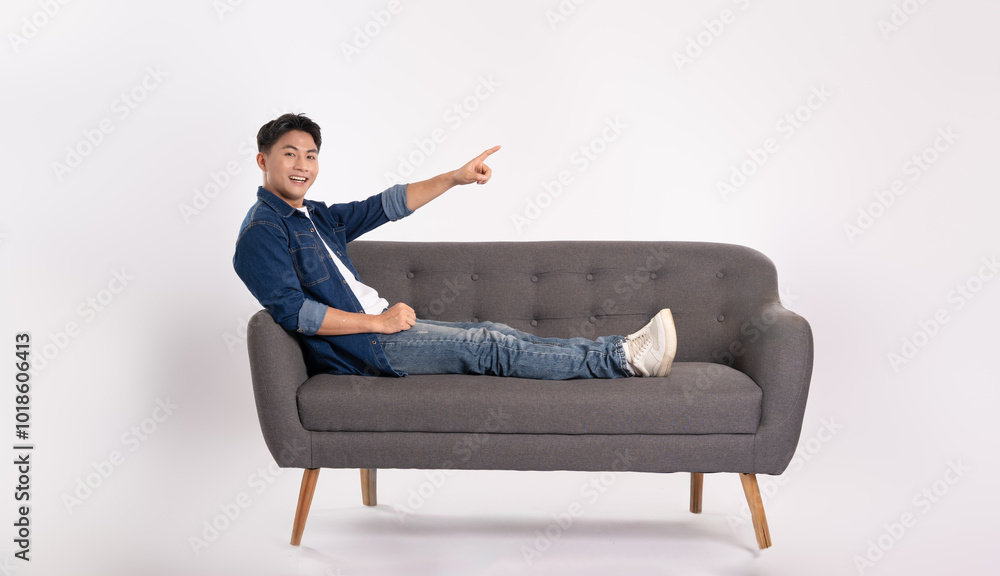 Full body image of young Asian man posing on sofa on white background Full body image of young Asian man posing on sofa on white background