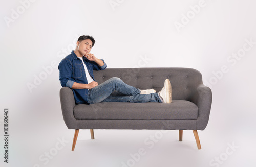 Full body image of young Asian man posing on sofa on white background