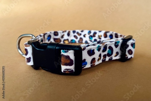 close up On a brown background lies a collar in a leopard color with a black plastic fastex clasp. pet accessories side view photo