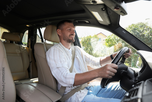 Smiling man holding steering wheel while driving car