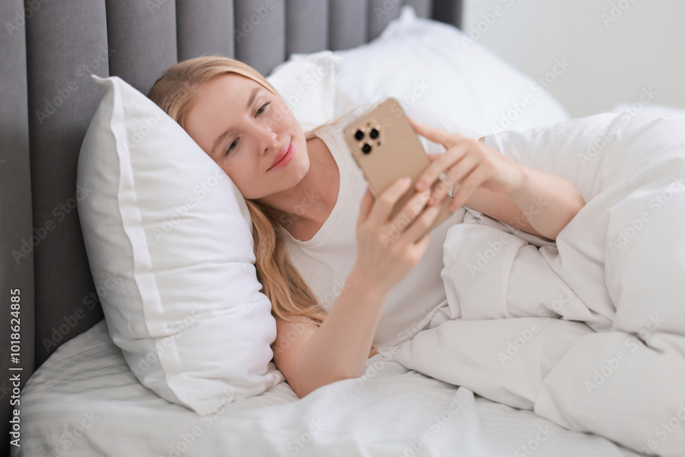 Beautiful woman looking at smartphone in bed Beautiful woman looking at smartphone in bed