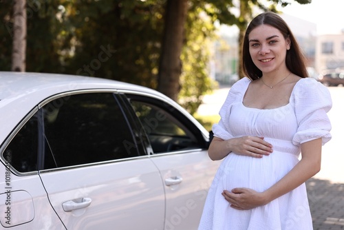 Portrait of smiling pregnant woman near car outdoors