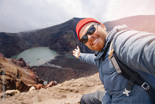 Trip adventure tour Kamchatka, Russia. Tourist man takes selfie photo against backdrop of Gorely volcano photo