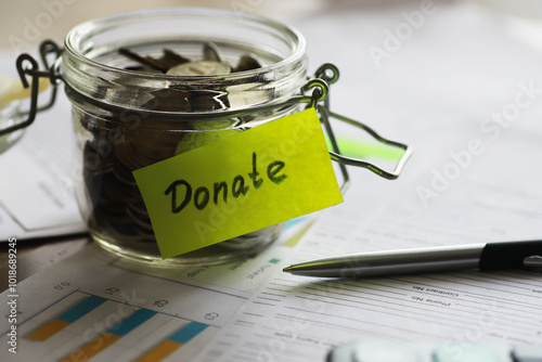 Glass Jar with Donation Coins on Financial Documents and Pen - Charity and Fundraising Concept photo