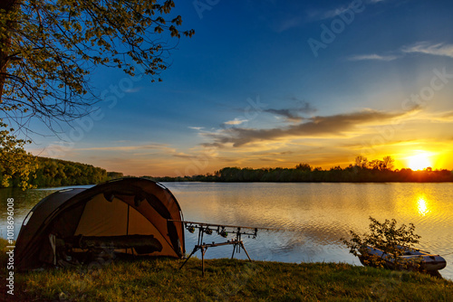 Fishing adventures, carp fishing. Angler, at sunset, is fishing with carpfishing technique. Camping on the shore of the lake.Carp Fishing Sunset