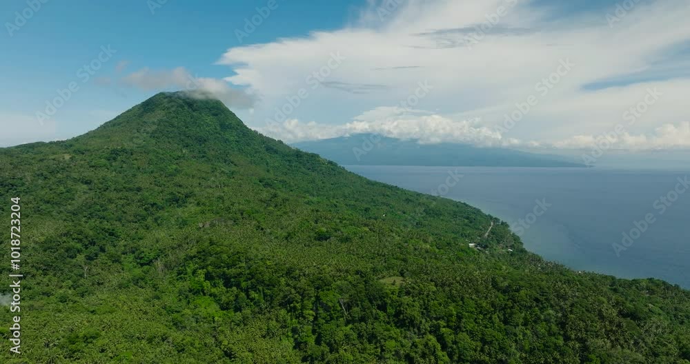 Aerial view of mountain hill with forest and jungle. Blue sky and clouds. Camiguin Island. Philippines. Aerial view of mountain hill with forest and jungle. Blue sky and clouds. Camiguin Island. Philippines.