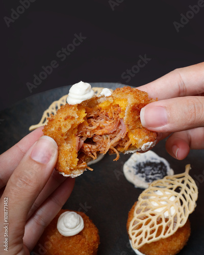 Mão segurando bolinho recheado com carne desfiada photo