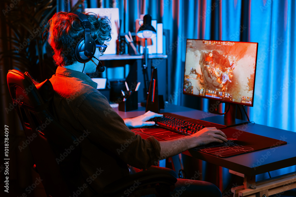 Host channel of young gaming streamer playing fighting Moba at battle arena game with multiplays team, wearing headphone on pc monitor with back side image at neon digital light modern room. Gusher. Host channel of young gaming streamer playing fighting Moba at battle arena game with multiplays team, wearing headphone on pc monitor with back side image at neon digital light modern room. Gusher.