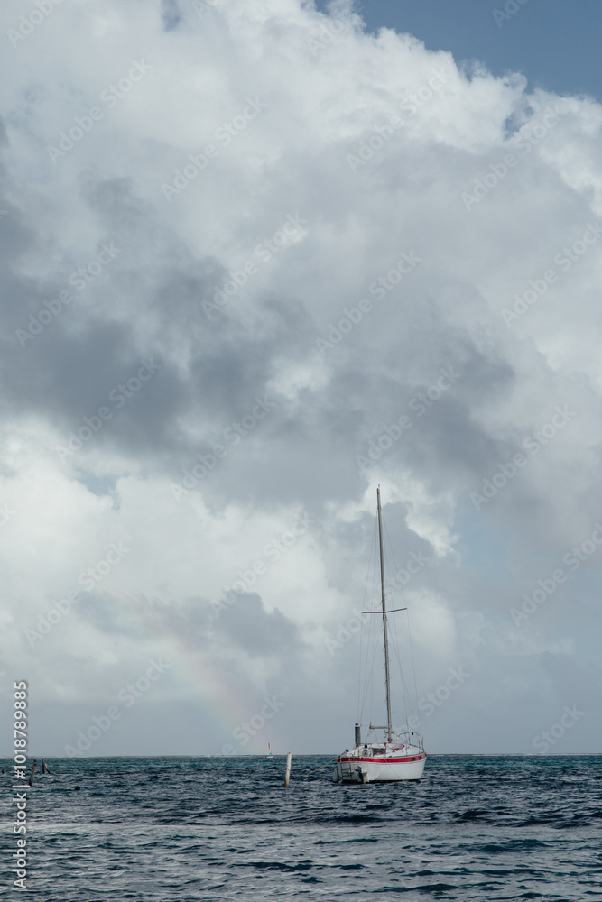 White boat on the ocean with a rainbow behind on a sunny day White boat on the ocean with a rainbow behind on a sunny day