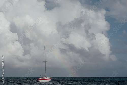 White boat on the ocean with a rainbow behind photo