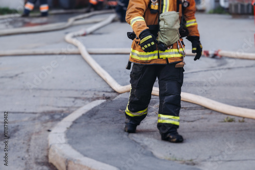 Group of fire men in uniform during fire fighting operation in the city streets, firefighters with the fire engine truck vehicle in the background, emergency and rescue, fire drill, exercise training