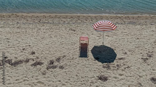 Aerial view of a sandy beach with beach chair and umbrella