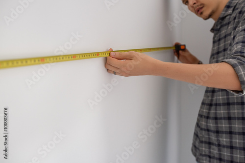 Focused man measuring wall photo