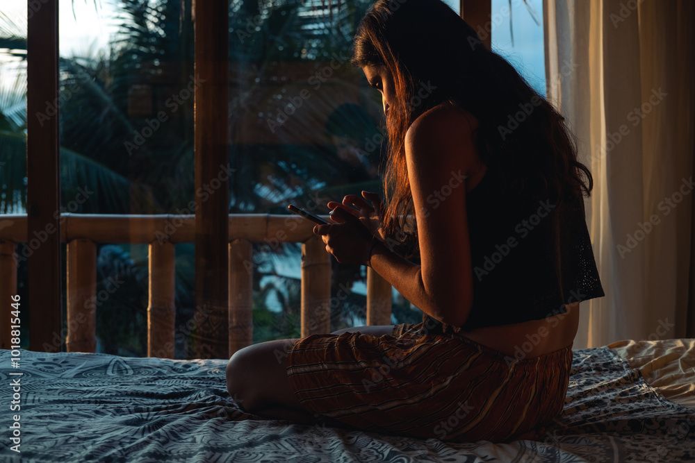 © Luis Herrera/Stocksy - young woman in bed with phone in dark room at dawn © Luis Herrera/Stocksy - young woman in bed with phone in dark room at dawn