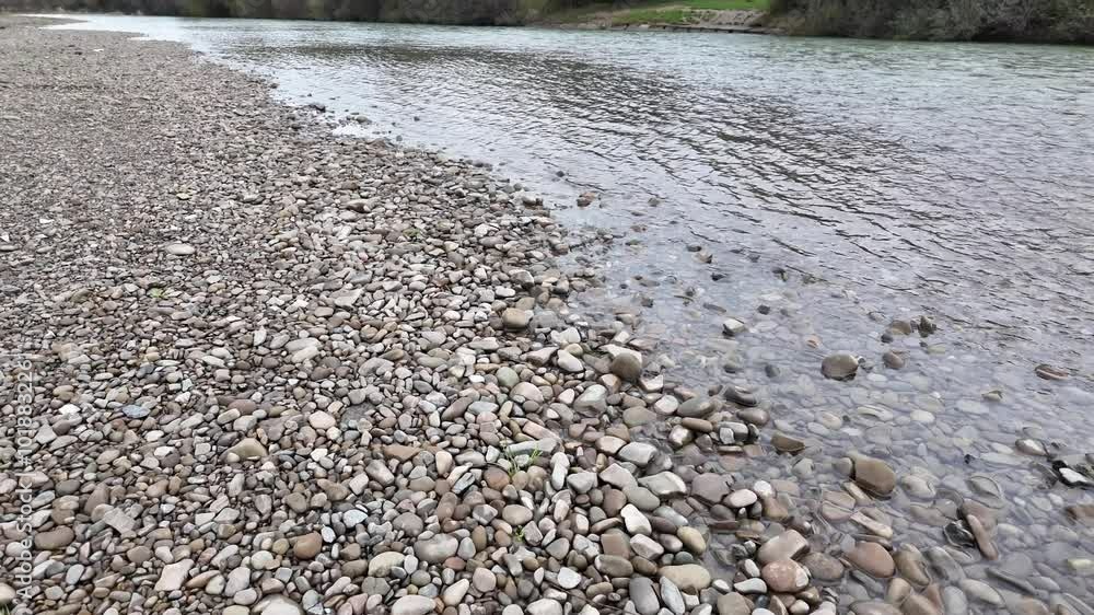 Flow of a clear mountain river. Shallow water of mountain river, the riverbank and clouds in the sky Flow of a clear mountain river. Shallow water of mountain river, the riverbank and clouds in the sky