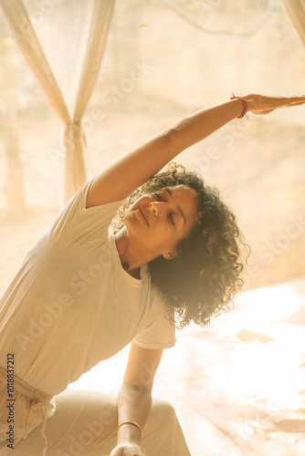 Woman Practicing Yoga Indoors with Curly Hair and Soft Light photo