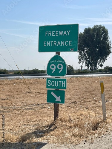 Entrance to the 99 South Freeway. Farmland and trees are visible in the background