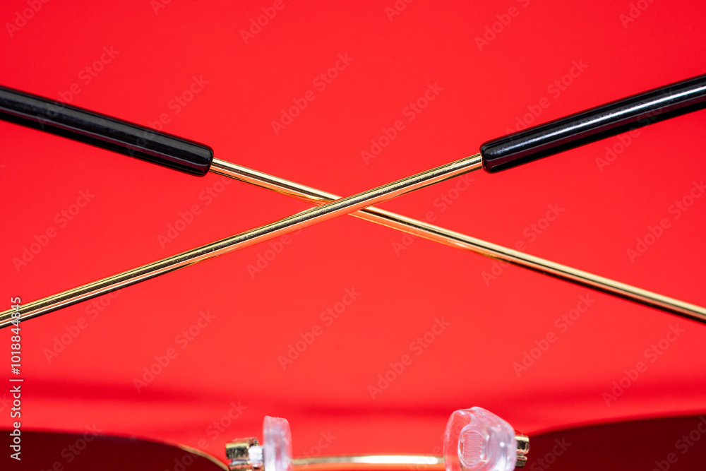 Gold colored sunglasses with a red background Gold colored sunglasses with a red background