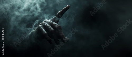 Pointing creepy zombie monster hand on dark smoky background. Halloween concept. Cinematic moody scene, horror movie theme.