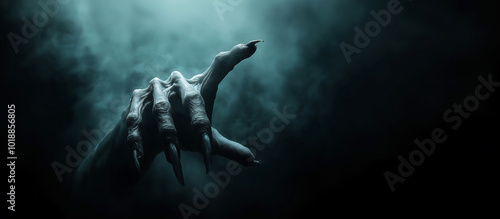 Pointing creepy zombie monster hand on dark smoky background. Halloween concept. Cinematic moody scene, horror movie theme.
