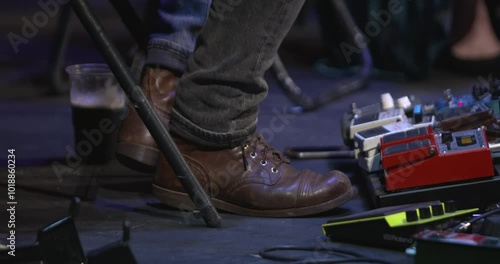 Musician taps his foot in time to music live stage performance guitar effects pedals