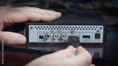 Wallpaper Mural Human hand connects audio cable to TV set-top box Torontodigital.ca