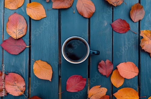 A cozy cup of coffee surrounded by autumn leaves on a wooden table in the aft...