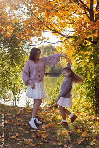 Obraz na płótnie mother and her daughter of seven years walk warm autumn in a park with trees at sunset in orange leaves. w salonie
