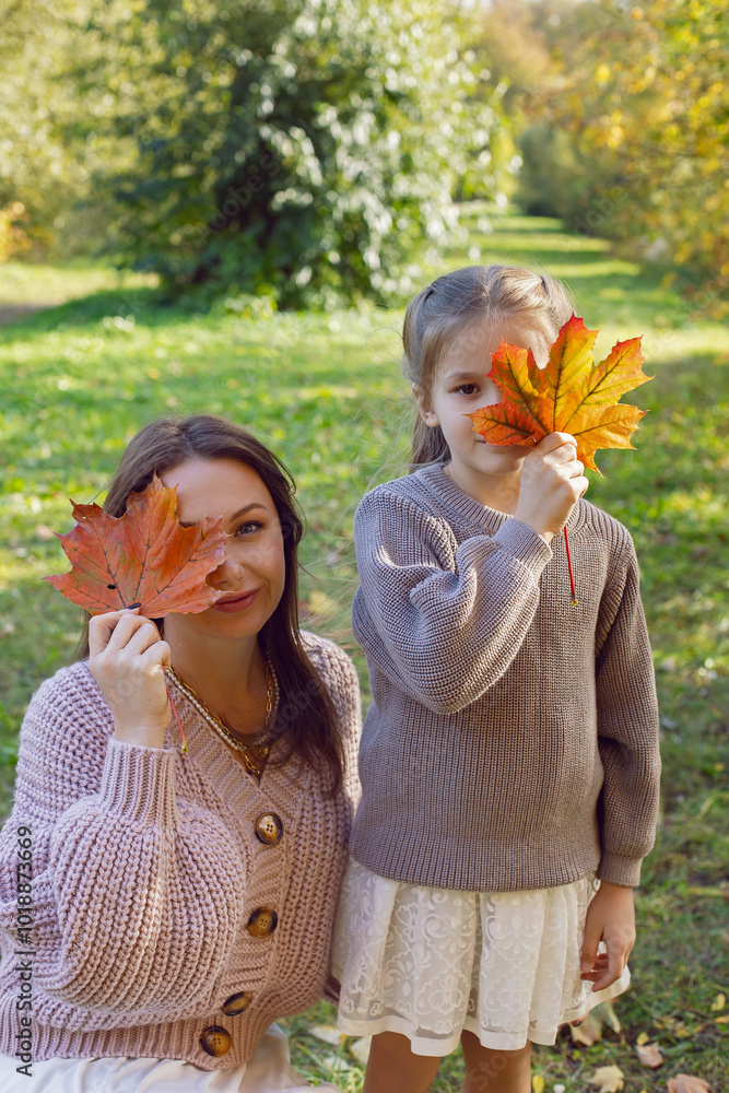 mother and her daughter of seven years walk warm autumn in a park with trees at sunset in orange leaves. cover your face