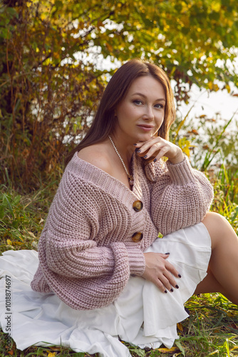 portrait of a woman in a dress sit in a park in autumn.