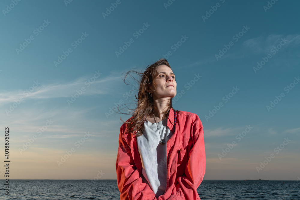 Woman in Red shirt Standing by the Sea at Sunset Woman in Red shirt Standing by the Sea at Sunset