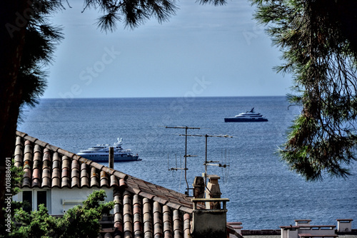 Cannes, France - September 7th 2024 : High view of the city. Focus on two boats on the sea, over a rooftop. photo