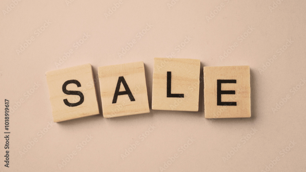 Obraz premium Word of Sale. Text written by wood toy or wood cubes on white paper background with texture. Top view of wooden english alphabet arranging to words. Close up of photo letter design wood toys.