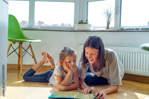 Young  Female babysitter  reads a book with a child on the floor  photo