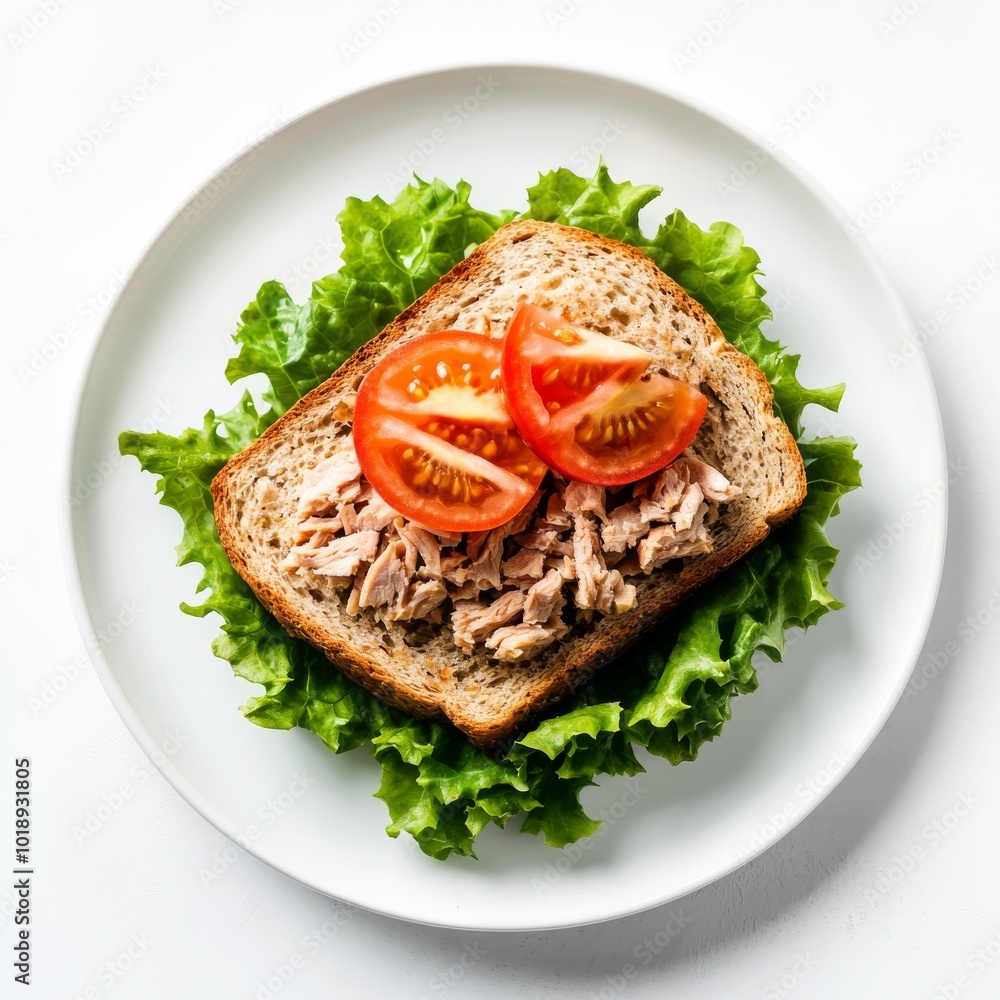 Tuna sandwich with fresh lettuce, tomato slices, and whole grain bread served on a white plate, ideal for a healthy lunch option, side and top view Tuna sandwich with fresh lettuce, tomato slices, and whole grain bread served on a white plate, ideal for a healthy lunch option, side and top view