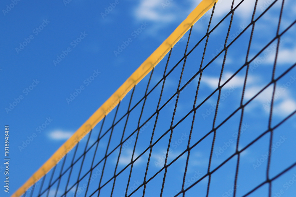 Beach volleyball net close-up. Fragment of a volleyball net on the beach against the blue sky. Sport, beach volleyball. Active recreation concept. Background. Detail of the yellow net. Sports ground Beach volleyball net close-up. Fragment of a volleyball net on the beach against the blue sky. Sport, beach volleyball. Active recreation concept. Background. Detail of the yellow net. Sports ground