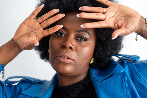 Confident Black Woman Framing Face With Hands In Blue Jacket photo