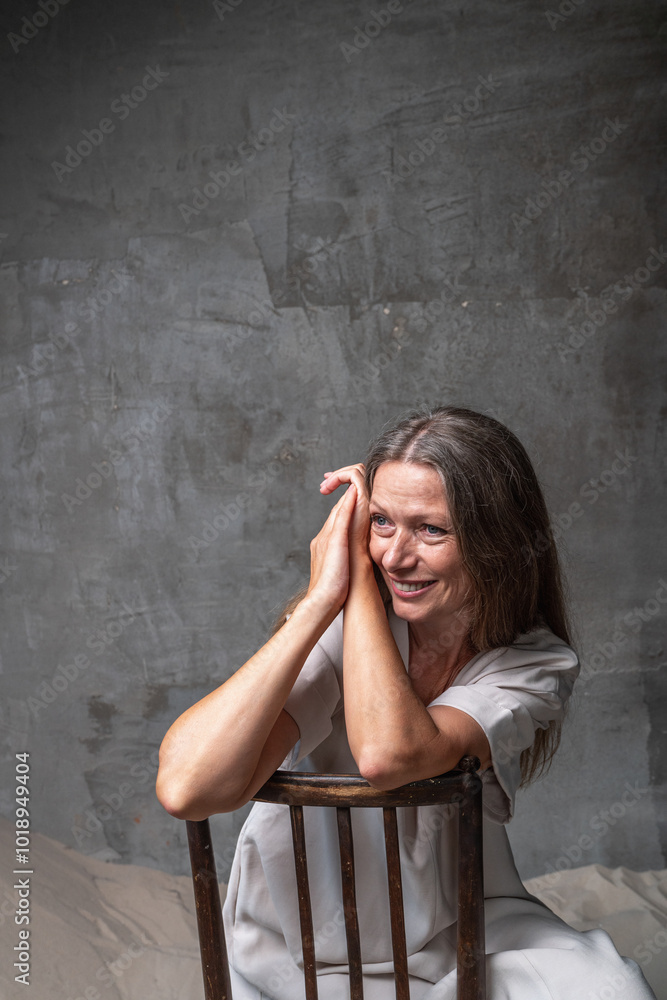 Smiling woman leaning forward on chair with hands clasped Smiling woman leaning forward on chair with hands clasped