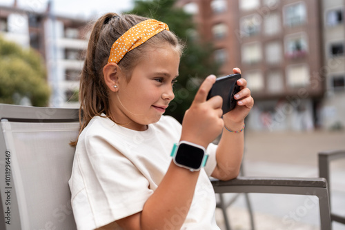 Girl is sitting outside playing a game on her smartphone photo