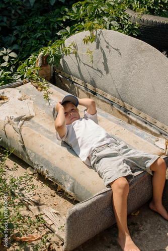 A Child Relaxing on an Old Couch Surrounded by Greenery Outdoors photo